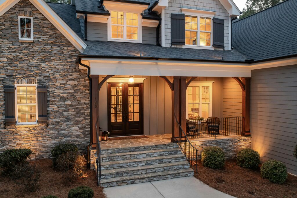 Front entrance of a suburban home featuring a stone facade and a covered porch with warm lighting and seating.