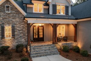 Front entrance of a suburban home featuring a stone facade and a covered porch with warm lighting and seating.